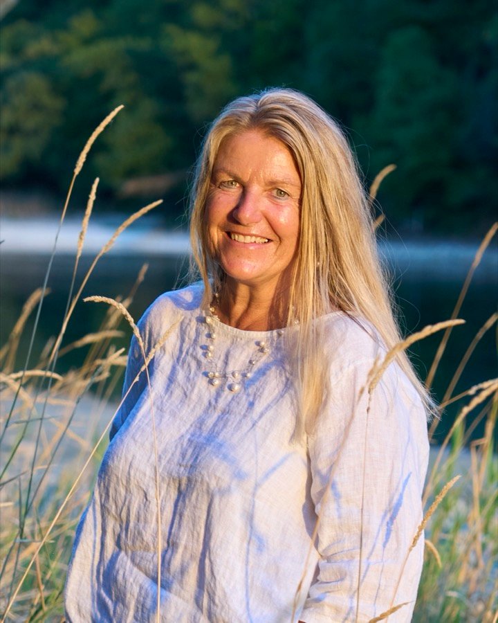 Barbara Anselstetter lächelnd im hohen Gras am Rheinufer, im warmen Abendlicht